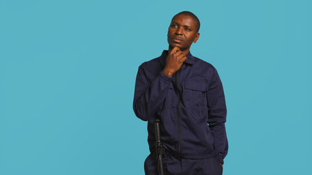 Security guard doing thinking hand gesture, being tasked with preventing criminal activity and detaining suspects. Portrait of pensive bodyguard rubbing chin, studio background, camera Bの写真素材