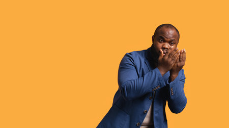 African american man covering face with hands to avoid being recognized, isolated over studio background. Distressed BIPOC person hiding from someone, putting palms in front of face, camera Bの写真素材