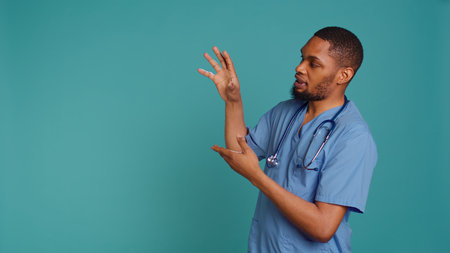 Male nurse pointing finger towards empty space doing advertising, talking with audience. Healthcare worker doing presentation, showing copy text, studio backdrop, camera Bの写真素材
