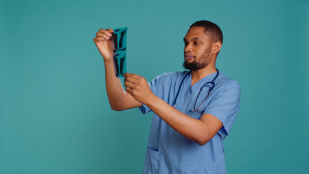 Male nurse talking with patient, giving him radiology x ray scan results, isolated over studio background. Medic presenting radiography and providing trauma treatment, camera Bの写真素材