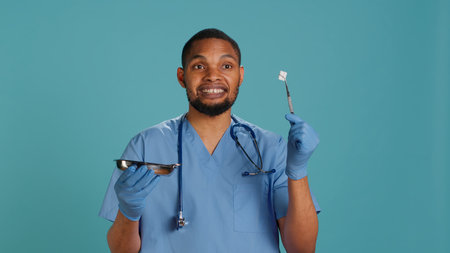 Professional male nurse in scrubs holds medical tools, explaining their use, providing expertise, studio background. Healthcare expert presenting surgical equipment, doing education, camera Aの写真素材