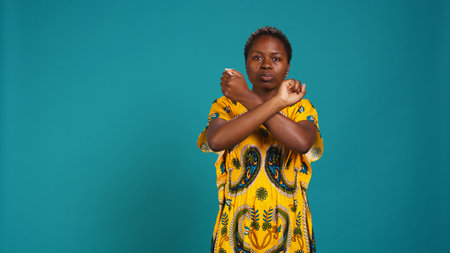 Dissatisfied unhappy person showing a refusal symbol with hands in a stop sign shape, expressing negativity and her rejection for something in studio. Young woman feels displeased. Camera B.の写真素材
