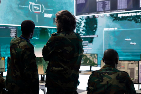 Military personnel discussing about enemy vessel trajectory in control room, analyzing data for defense program mission in command center. Army staff gathering intelligence from big screen.の写真素材