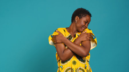 Confident young woman representing her african ethnicity by wearing a tribal native dress with floral elements in studio. Sweet natural girl embracing herself being proud of her origins. Camera A.の写真素材