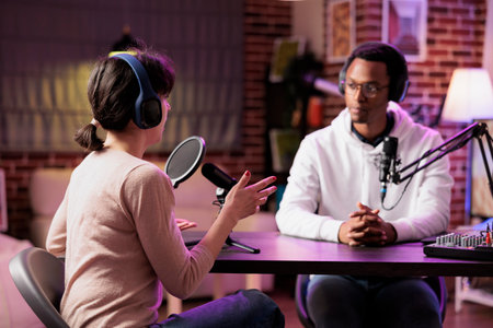 African american podcast host discussing with guest during live broadcast for social media website, listening to her story. Internet star using professional equipment to record chatの写真素材