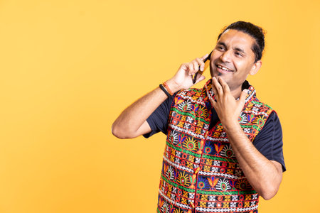 Gleeful man communicating with hilarious friend over telephone call, having fun. Happy person laughing, thrilled to hear comical jokes from mate during phone call, studio backgroundの写真素材