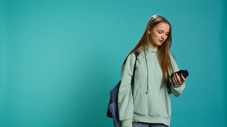 Young girl suffering from illness upset about needing to take medicine, holding pill bottle. Ill woman preparing to take need dose of vitamin supplements, studio background, camera Bの写真素材