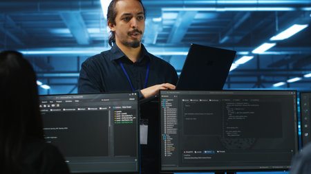 Manager in data center doing annual system review, checking parameters on laptop. Supervisor...