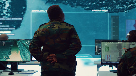 Woman army officer coordinating special operations mission in command post, monitoring surveillance satellite footage on big screen in military power base. Female soldier on duty. Camera A.の写真素材