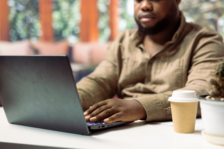 Entrepreneur working remotely on his online business tasks, using a laptop to carry out audit operations and achieve objectives. Freelancer telecommuting for his job. Close up.の写真素材