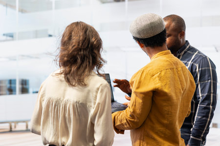 Business professionals evaluating real estate blueprints on a laptop, discussing with the realtor about a potential investment contract deal. High class urban relocation for development.の写真素材