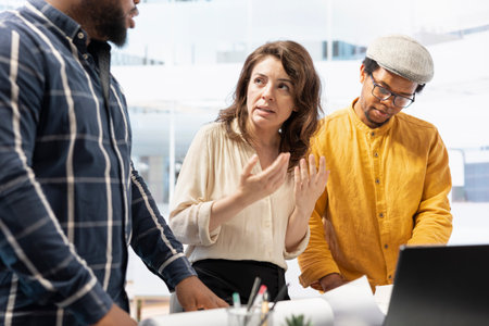 Corporate clients and their real estate agent engage in a detailed planning session, discussing the layout and design of a new office space based on blueprints. Office tour for relocation.の写真素材