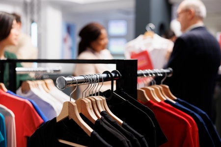 Seasonal shopping. Close up of different branded clothes hanging on garment rack in fashion outlet,...