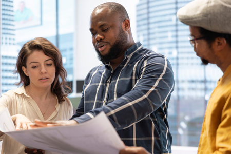Entrepreneur talking about an investment in real estate office space, discussing with real estate agents team during an office tour. Detailed blueprints and the layout of the urban property.の写真素材