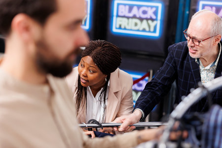 Rude unpleasant shoppers arguing and fighting while hunting for Black Friday deals in clothing store, grabbing discounted fashion items and yelling at each other. People fight over clothes in mallの写真素材