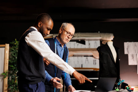 Fashion designers looking online for inspiration, trying to come up with artistic creative haute couture sartorial collection. Teamworking couturiers brainstorming upcoming menswear assortmentの写真素材