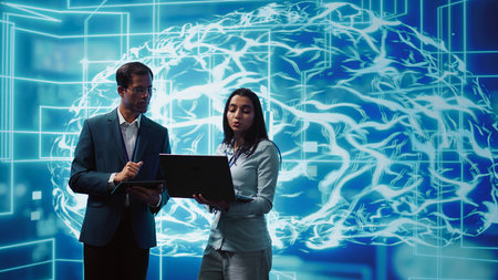 Coworkers solving tasks on laptop and tablet, running artificial intelligence programming scripts. IT staff members using devices to write lines of code for AI applications development, camera Bの写真素材