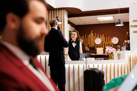 Business traveller arriving at front desk in hotel, talking to receptionist for check in process. Businessman travelling for important meetings abroad, asking for services to ensure pleasant stay.の写真素材