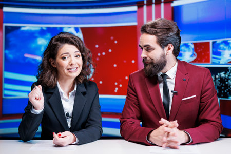 Team of presenters doing newscast live on tv channel, broadcasting daily headlines in newsroom. News anchors colleagues working on television industry, presenting latest events.の写真素材