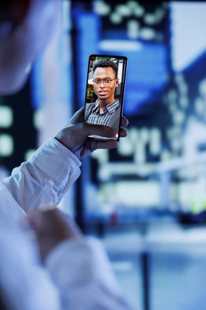 Woman in videocall with boyfriend while strolling around city streets at night, close up. Citizen using smartphone to show partner surroundings in dimly illuminated town center in blurry backgroundの写真素材