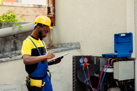 Trained engineer doing leak checks, filter replacements and necessary repairs to prevent major breakdowns. Knowleadgeable technician troubleshooting air conditioner, writing findings on clipboardの写真素材