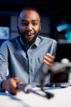 BIPOC influencer using smartphone to film vlog channel intro for online streaming platforms. Media star greets fanbase, presenting today video topic, recording with phone, close upの写真素材