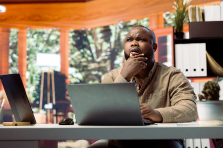 Freelancer managing startup projects and thinking about client needs from his home office, developing new growth strategy. Self employed analyst does telecommuting work on laptop.の写真素材