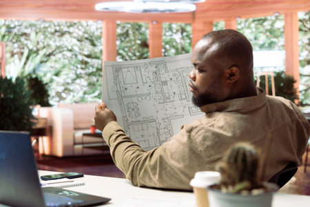 Small business owner analyzing architectural sketches and planning office spaces, focusing on...