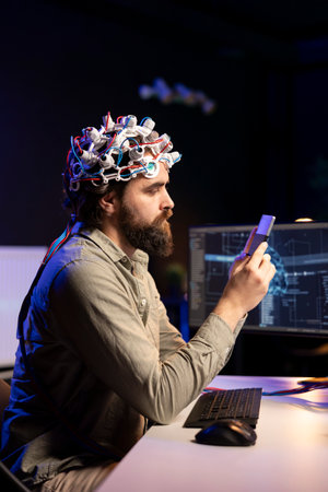 Engineer with EEG headset inserting cartridge into PC to use high tech software allowing for brain transfer into virtual world. Man putting disk in computer to start consciousness uploadの写真素材