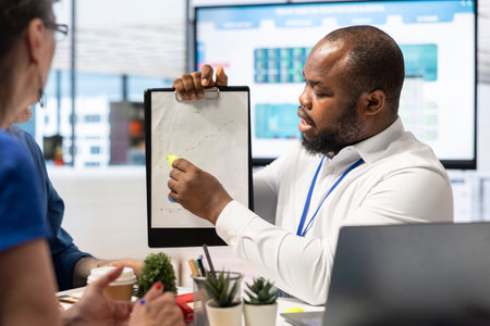 Insurance broker explaining financial plans to senior couple in a modern office, receiving expert advice on retirement plans. Discussing investment strategy, pension options and savings.の写真素材