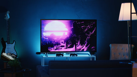Zoom in shot on TV screen showing 3D render animations in empty stylish neon lit home studio interior. Modern apartment illuminated with RGB lights at night and artwork decorating the wallsの写真素材