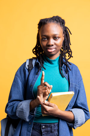 Portrait of woman with textbook gathering information for school exam, isolated over studio background. Young african american girl holding book, preparing for university assessmentの写真素材