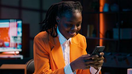 African american girl texting messages on smartphone, taking a break from working on her bachelor...