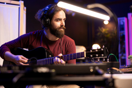Musical artist mixing and mastering guitar tunes played on acoustic instrument, using electronic controls on console and daw software. Songwriter producer creating new sounds, home studio.の写真素材