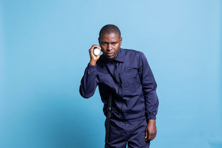African american security agent patrolling the mall perimeter in the dark, using his flashlight to control the premises at night. Armed skilled guard inspecting the area with a lantern.の写真素材