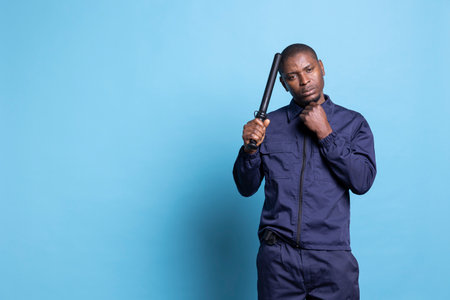 Security officer poses with a police baton and his fist clenched, making threats in case of attack or emergency fights. Guard on protection duty trained to punch and use his uniform weapon.の写真素材