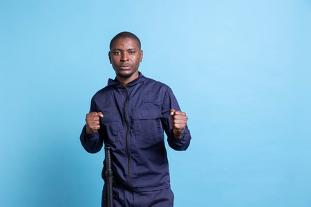 Professional security agent with clenched fists is ready for a fight in studio, throw punches while on protection and defense duty. Guard protecting the premises, taking safety measures and fighting.の写真素材