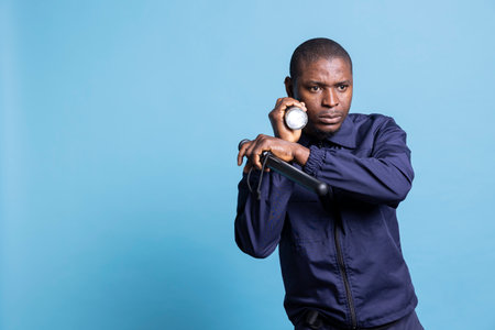 Mall security guard doing a control sweep during his night patrol duty, using a flashlight in the dark and holding his baton. Agent using a lantern to ensure safety on the perimeter.の写真素材