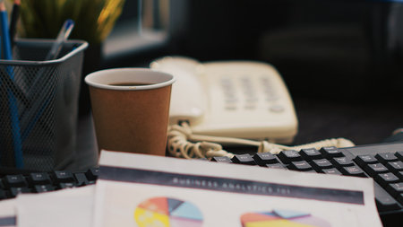 Corporate project investments report on desk next to paper cup of coffee, close up shot. Bookkeeping documents containing business analytics near hot beverage on table in officeの写真素材