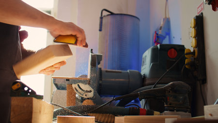 Woodworking specialist using manual sandpaper to sander lumber block, making furniture in assembling...