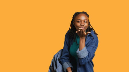 Frisky playful woman blowing kisses to camera, being flirty. Lively charming girl having fun sending air kisses, doing romantic gesturing, isolated over studio background, camera Aの写真素材