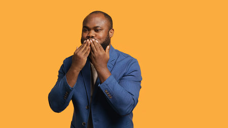 Frisky playful african american man blowing kisses to camera, being flirty. Lively charming BIPOC person having fun sending air kisses, doing romantic gesturing, studio background, camera Aの写真素材