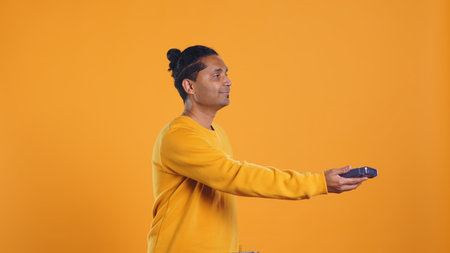 Indian pizza delivery worker getting takeaway order out of thermal backpack, giving it to client paying with card. Courier offering lunch paper bag and POS to customer, studio background, camera Bの写真素材