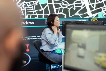 Call center operator puts headphones on to handle order delays complains from customers, working to ensure faster delivery time via satellite map and CCTV system. Cargo tracing.の写真素材