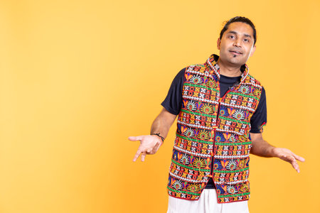 Portrait of upbeat man wavering, oscillating between answers, shrugging shoulders. Radiant person doing questioning hand gesturing, hesitating to provide response, isolated over studio backgroundの写真素材