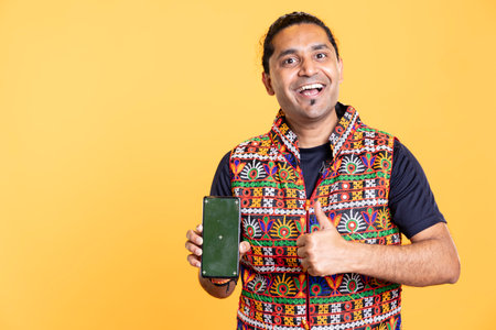 Portrait of excited content creator influencer smiling and doing thumbs up gesturing presenting isolated screen mobile phone. Thrilled person holding mockup cellphone, doing positive hand gestureの写真素材