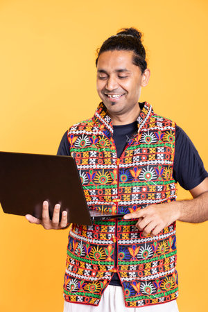 Portrait of jolly man grinning, happy after solving business tasks using laptop, isolated over studio background. Joyous employee celebrating finishing company budgeting using on notebookの写真素材