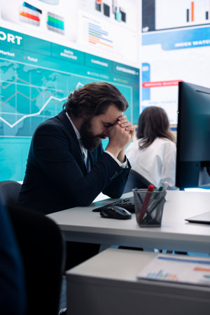 Stressed business manager working under pressure to meet deadline, sitting at his desk and thinking of ways to increase profit and organizational success. Corporate work frustration.の写真素材