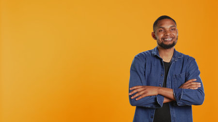 Portrait of african american casual man posing against orange background, showing confidence and determination in studio. Charismatic serious guy in stylish clothes. Camera B.の写真素材