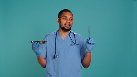 Portrait of doctor holding surgical equipment, preparing to do medical procedure, studio background. Healthcare expert gathering surgery tools needed for operation, camera Bの写真素材